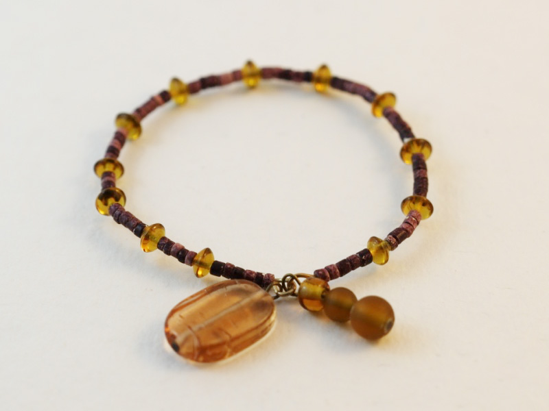 A beaded bangle made with purple ceramic beads and yellow glass beads.