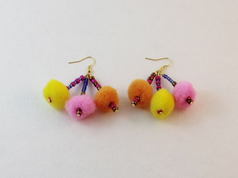 The completed earrings are the result of the pom pom dangle earring tutorial.