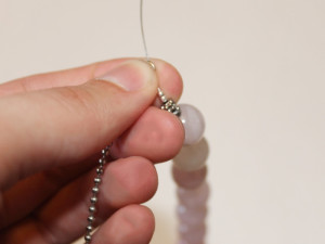 Threading the tiger tail wire through the end of the ball chain.