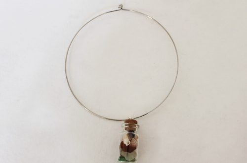a choker necklace with a charm filled with sea glass and shells