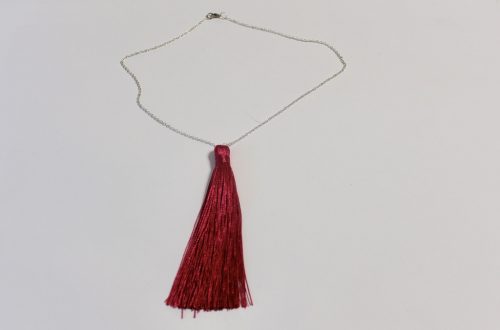 A silver chain necklace with a hot pink tassel pendant